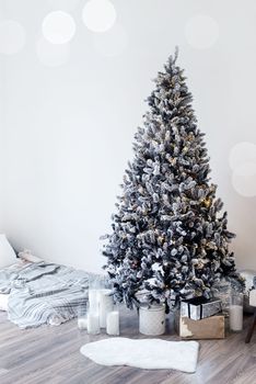 Merry Christmas and Happy New Year. Christmas tree with presents and lights in light and airy living room next to the window