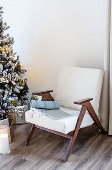 Merry Christmas and Happy New Year. Christmas tree with presents and lights in light and airy living room next to the window