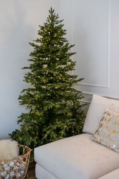 Merry Christmas and Happy New Year. Christmas tree with presents and lights in light and airy living room next to the window