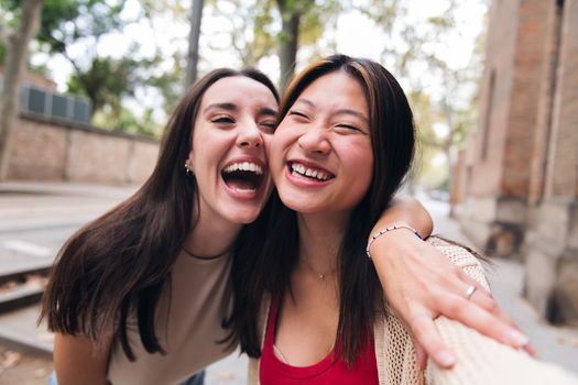 selfie of two young women laughing and having fun while dating, concept of friendship and love between people of the same sex