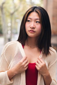 vertical portrait of a serious young asian woman looking to the side, concept of youth and beauty