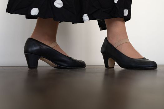 legs of woman dancing flamenco with black clothes on wooden floor and white background