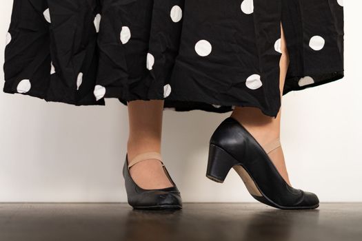 legs of woman dancing flamenco with black clothes on wooden floor and white background