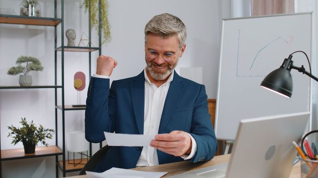 Mature business man open envelope letter, reading it. Career growth advance promotion, bank loan approve, successful admission to monetary award, long-awaited invitation, great news, lottery game win