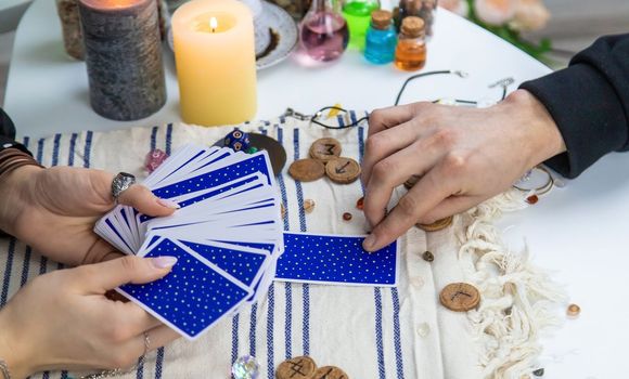A woman fortuneteller tells a man on tarot cards. Selective focus. People.