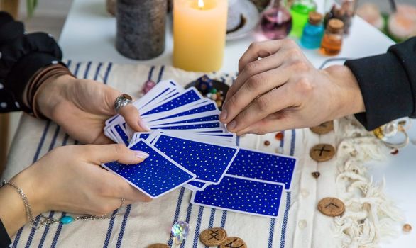 A woman fortuneteller tells a man on tarot cards. Selective focus. People.
