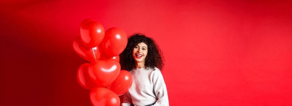 Holidays and celebration. Happy woman posing with party balloons on red background.