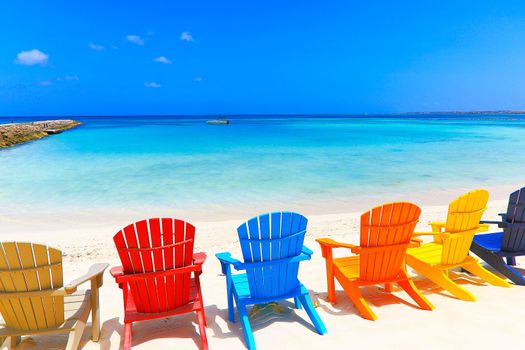 Colorful wooden chairs on white sand beach in Aruba, Duth Caribbean at sunny day