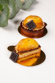 Whole and sliced shortbread tartlets filled with almond cream topped with chocolate ganache, caramelized apples and nuts on golden cardboard. Delicious handmade author pastries concept