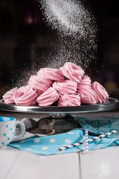 Pile of pink swirls of tender natural berry zephyr sprinkled with powdered sugar on dessert stand. Popular healthy sweet treats