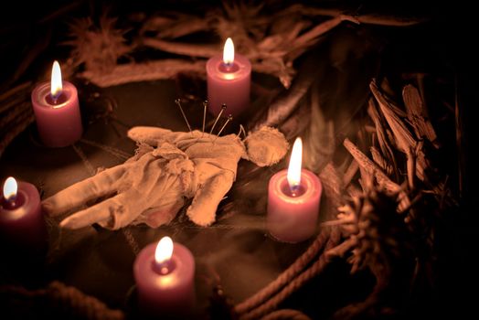Voodoo doll, black candles, pentagram and old books on witch table. Occult, esoteric, divination and wicca concept. Mystic, voodoo and vintage background