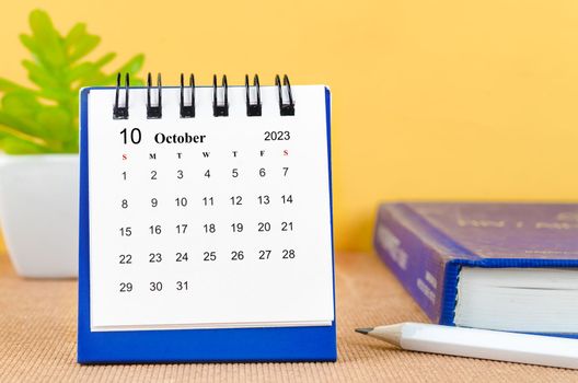 A October 2023 desk calendar with a book.