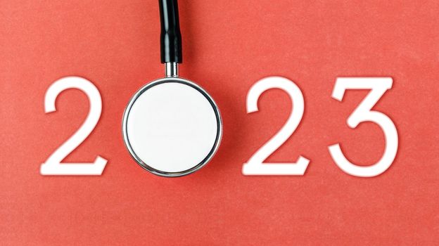 Stethoscope with number 2023 on red background. Happy new year for health care and calendar cover