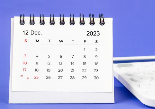 December 2023 Monthly desk calendar for 2023 year with calculator on purple background.