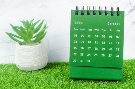 Green October 2023 Monthly desk calendar for 2023 year on grass.