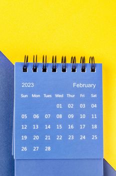 February 2023 Monthly desk calendar for 2023 year on blue and yellow background.