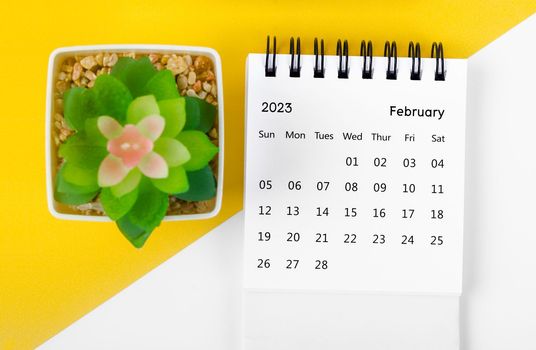 February 2023 Monthly desk calendar for 2023 year with small tree on yellow background.