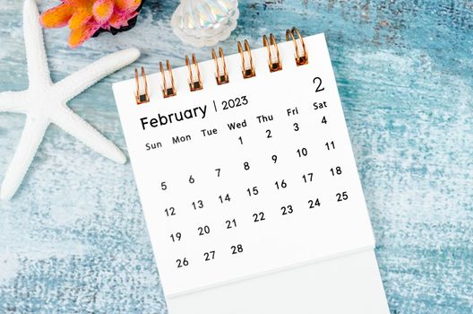 February 2023 Monthly desk calendar for 2023 year on old blue wooden background.