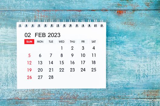 February 2023 Monthly desk calendar for 2023 year on old blue wooden background.