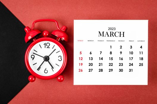 March 2023 Monthly calendar year with alarm clock on red and black background.