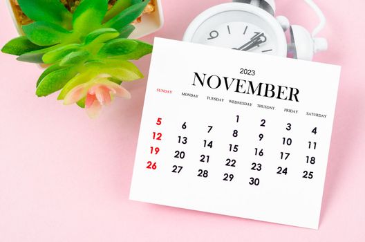 November 2023 Monthly calendar for 2023 year with vintage alarm clock on pink colour background.