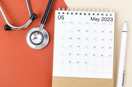 Stethoscope medical and May 2023 desk calendar with pen on the beautiful background, schedule to check up healthy concepts.