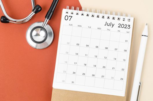 Stethoscope medical and July 2023 desk calendar with pen on the beautiful background, schedule to check up healthy concepts.