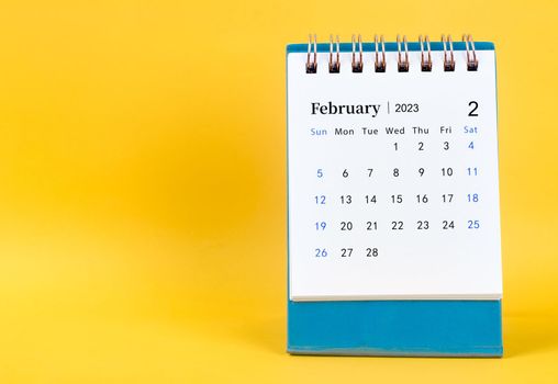 February 2023 desk calendar on yellow color background.