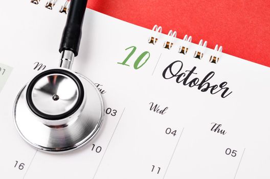 Stethoscope medical and October 2023 desk calendar on the red background, schedule to check up healthy concepts.