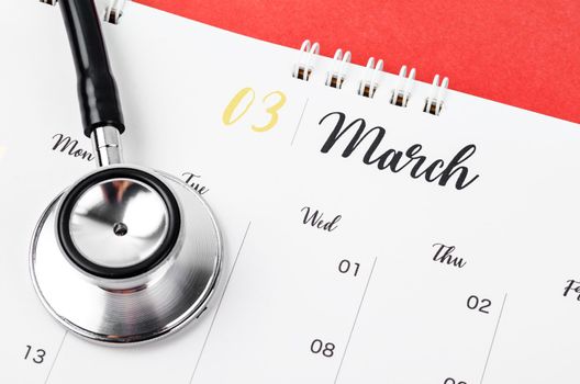 Stethoscope medical and March 2023 desk calendar on the red background, schedule to check up healthy concepts.