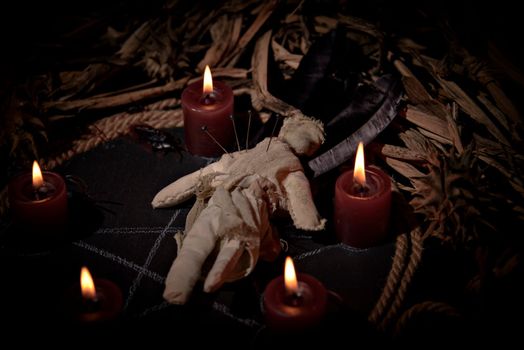 Voodoo doll, black candles, pentagram and old books on witch table. Occult, esoteric, divination and wicca concept. Mystic, voodoo and vintage background