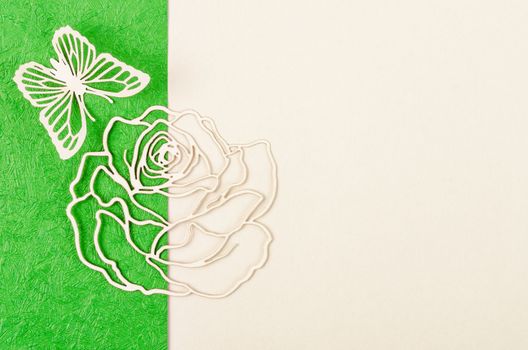 Butterfly and rose flower made from carve paper or cutting on green and yellow background with empty space for your text or message.
