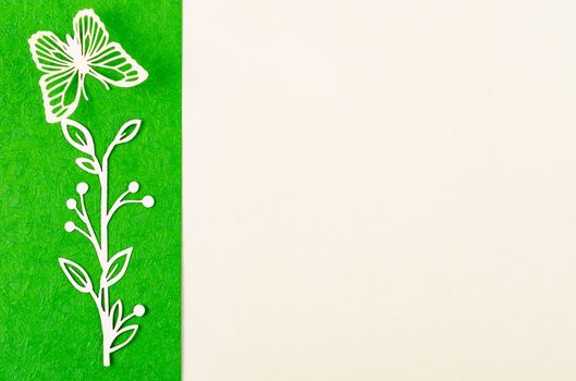 Butterfly and flower made from carve paper or cutting on green and yellow background with empty space for your text or message.