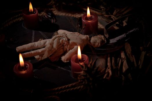 Voodoo doll, black candles, pentagram and old books on witch table. Occult, esoteric, divination and wicca concept. Mystic, voodoo and vintage background