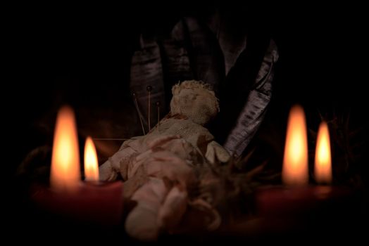 Voodoo doll, black candles, pentagram and old books on witch table. Occult, esoteric, divination and wicca concept. Mystic, voodoo and vintage background