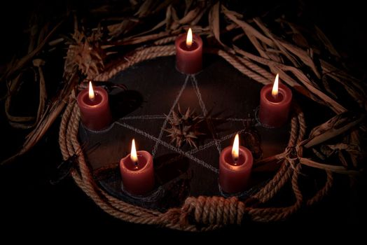 Voodoo doll, black candles, pentagram and old books on witch table. Occult, esoteric, divination and wicca concept. Mystic, voodoo and vintage background