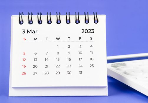March 2023 Monthly desk calendar for 2023 year with calculator on purple background.