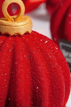 Closeup of Christmas ball shaped pastries covered with scabrous sparkling red and gold sugar glaze on white background. Creating festive mood and atmosphere with delicious desserts