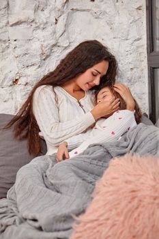 Mother and daughter sitting on sill near window in room. The daughter sleeping on mother's hands