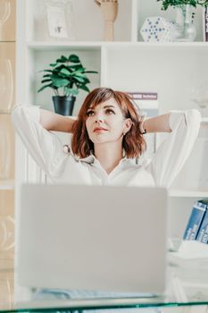 Office laptop woman. Calm smiling businesswoman relaxing on comfortable office chair hands behind head, happy woman resting in office satisfied after work, enjoying break, peace of mind, no stress.