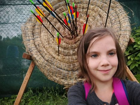 Archery for child. Little girl with bow and arrow. Kids shoot on tropical island. Target on outdoor shooting range. Archer club for young children. Healthy summer activity. High quality photo
