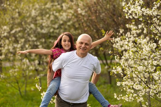 Adorable cute girl and grandfather walk in park