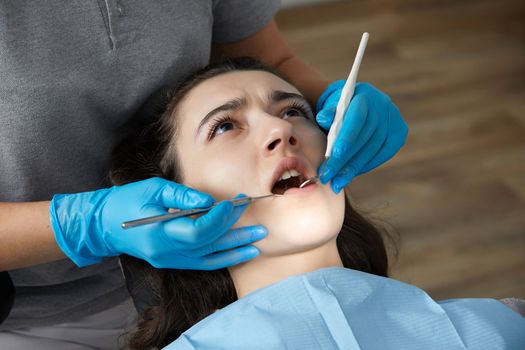 Dentist checking teeth of a patient with dental mirror. Woman having teeth examined at dentists