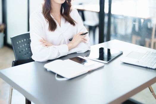 Portrait of a woman business owner showing a happy smiling face as he has successfully invested her business using computers and financial budget documents at work.