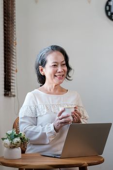 Smart asian mature middle-aged businesswoman CEO boss leader teacher using laptop, e-learning , working remotely online in home office.
