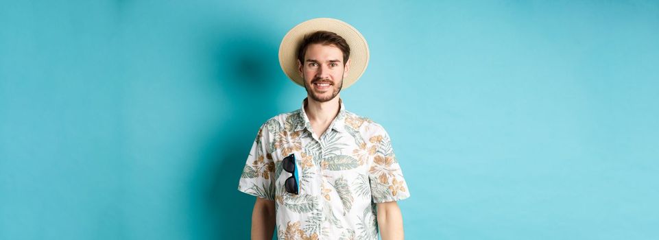 Happy and positive tourist in hawaiian shirt and straw hat, smiling at camera. Concept of tourism and summer holiday.