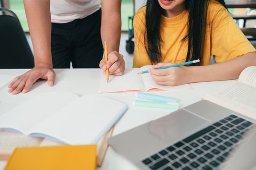 Young woman and man studying for a test or an exam. Tutor book with friends. Young students campus or classmates helps friend catching up workbook and learning tutoring in classroom, teaching, learning