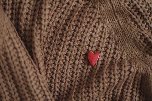 Decorative red heart on beige knitted texture background. Valentines day or love concept.