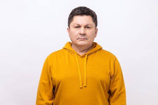 Portrait of serious self assured unsmiling man with dark hair seriously looking at camera, confidence, wearing urban style hoodie. Indoor studio shot isolated on white background.