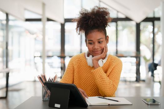 Young black curly hair American African woman using digital tablet.